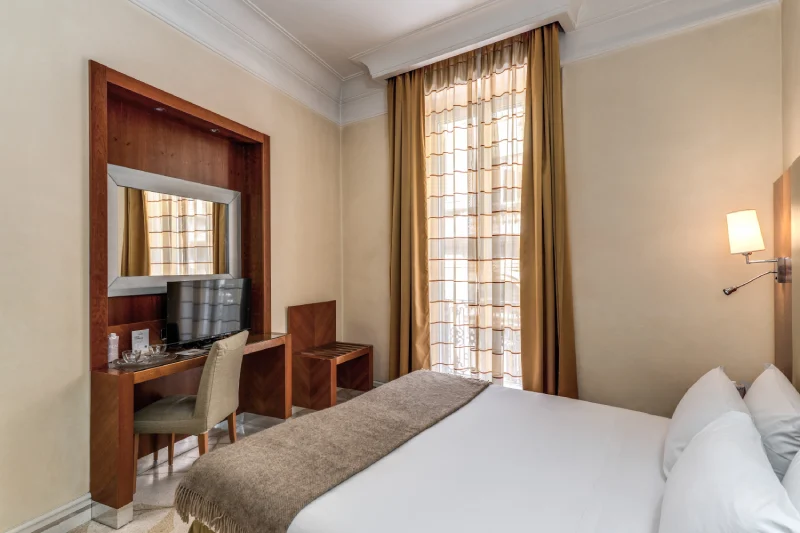 Camera matrimoniale con scrivania, TV e finestra con tende, stile classico vicino Teatro dell’Opera Roma - Depandance Opera, BZAR hotels a Roma