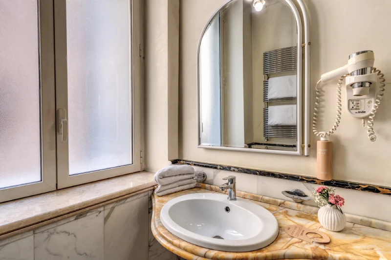 Bagno con lavabo in marmo, specchio e asciugacapelli in ambiente elegante vicino Teatro dell’Opera Roma - Depandance Opera, BZAR hotels a Roma