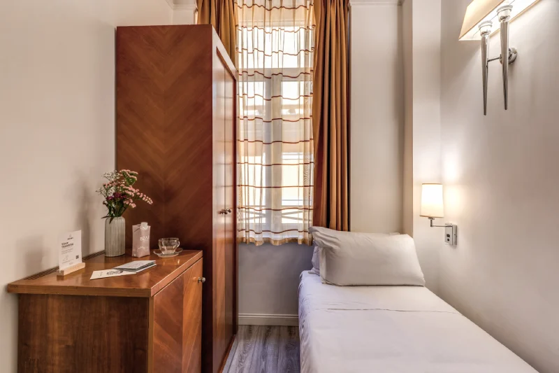 Camera singola luminosa con letto singolo, armadio in legno e finestra vicino Teatro dell’Opera Roma - Depandance Opera, BZAR hotels a Roma