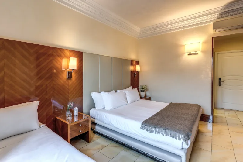 Letto matrimoniale con comodino e luci calde, affiancato da letto singolo in camera per famiglie a Roma centro vicino Teatro dell’Opera - Hotel Sonya, BZAR hotels a Roma